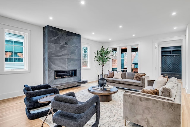 living room featuring a high end fireplace and light hardwood / wood-style flooring