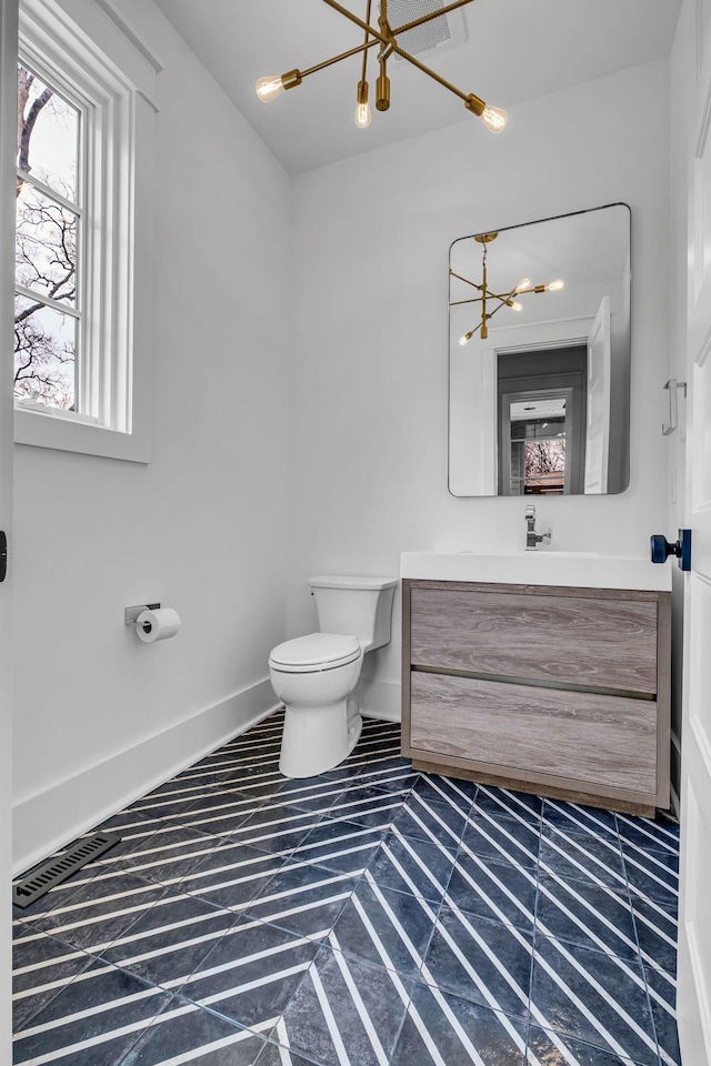 bathroom with vanity, toilet, and a chandelier