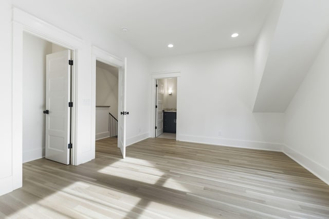 unfurnished bedroom with a walk in closet, ensuite bath, and light hardwood / wood-style flooring