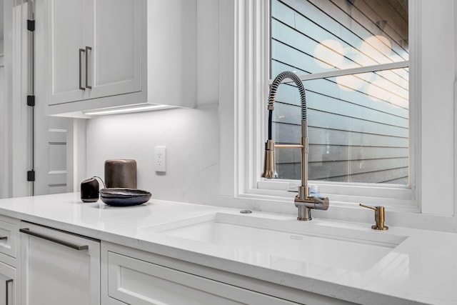 kitchen with white cabinetry, light stone countertops, sink, and a wealth of natural light