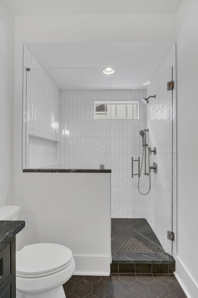 bathroom featuring vanity, tile patterned floors, toilet, and tiled shower