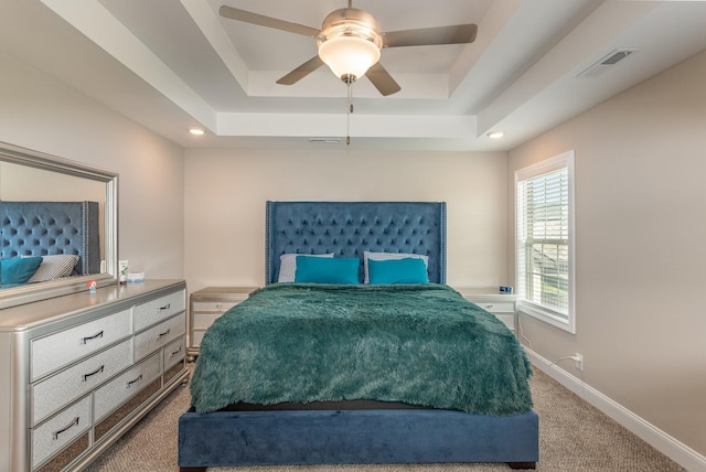 carpeted bedroom featuring ceiling fan and a raised ceiling