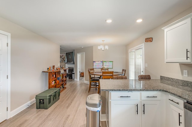 kitchen with light stone counters, white cabinetry, light hardwood / wood-style flooring, and kitchen peninsula