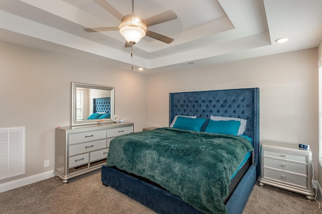 carpeted bedroom with ceiling fan and a tray ceiling