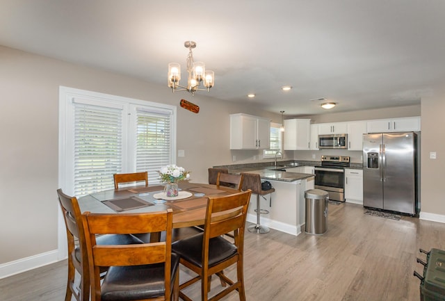 dining area featuring sink, a chandelier, and light hardwood / wood-style flooring