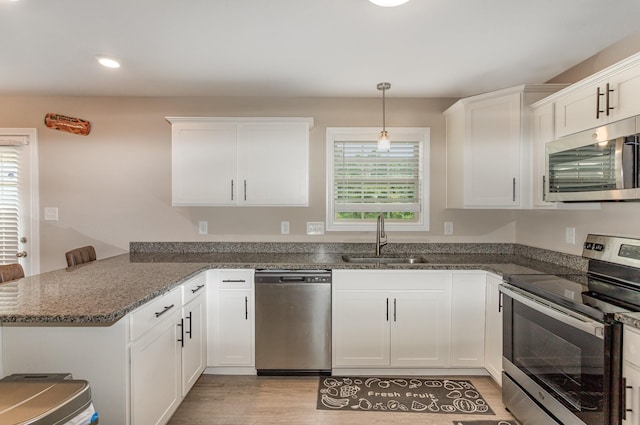 kitchen featuring appliances with stainless steel finishes, white cabinetry, decorative light fixtures, and sink