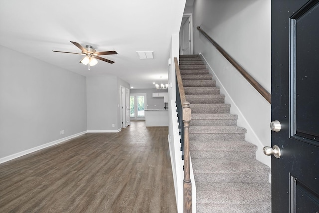 staircase with ceiling fan with notable chandelier and hardwood / wood-style flooring