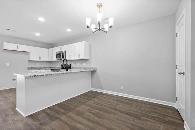 kitchen featuring light stone countertops, white cabinetry, dark wood-type flooring, hanging light fixtures, and kitchen peninsula