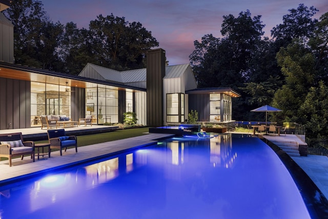 pool at dusk with a shed, an outdoor living space, and a patio