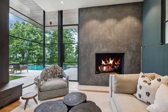 living room featuring a large fireplace, a wall of windows, and light hardwood / wood-style flooring