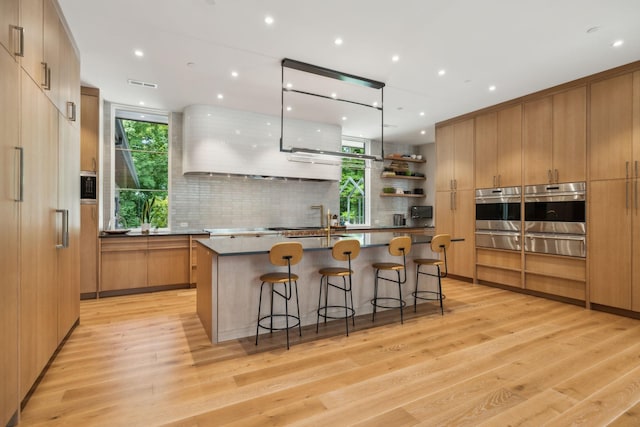 kitchen featuring a center island with sink, oven, and light hardwood / wood-style flooring