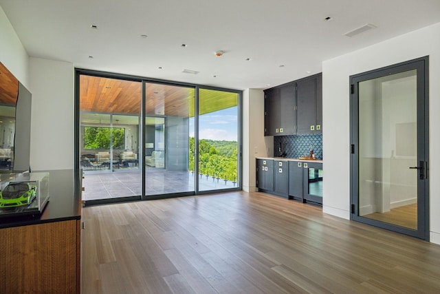 interior space featuring backsplash, light hardwood / wood-style floors, and expansive windows