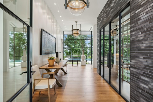 interior space featuring a wall of windows, a notable chandelier, light hardwood / wood-style floors, plenty of natural light, and french doors