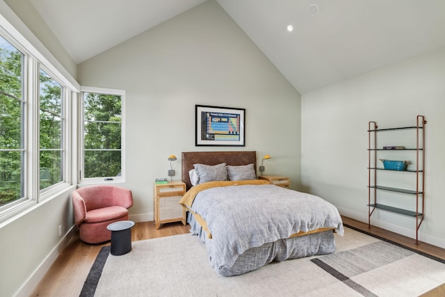 bedroom with multiple windows, high vaulted ceiling, and light hardwood / wood-style flooring