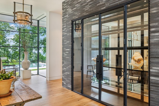 doorway featuring a notable chandelier, hardwood / wood-style flooring, plenty of natural light, and expansive windows