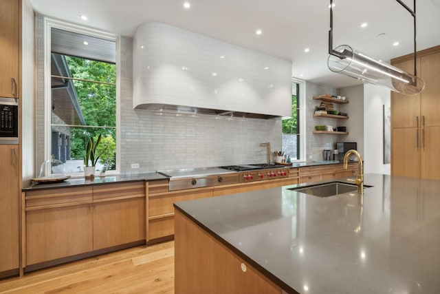 kitchen featuring appliances with stainless steel finishes, sink, light hardwood / wood-style floors, and decorative backsplash