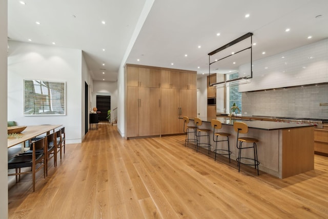 kitchen featuring pendant lighting, a large island, light hardwood / wood-style floors, and a breakfast bar area