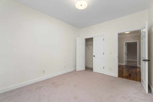 unfurnished bedroom with baseboards, a closet, and light colored carpet