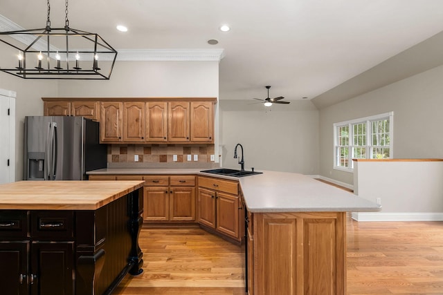 kitchen with a sink, a kitchen island, stainless steel fridge, and light wood-style floors