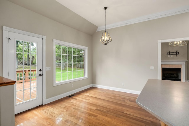 unfurnished dining area featuring a chandelier, a fireplace, visible vents, baseboards, and light wood-style floors