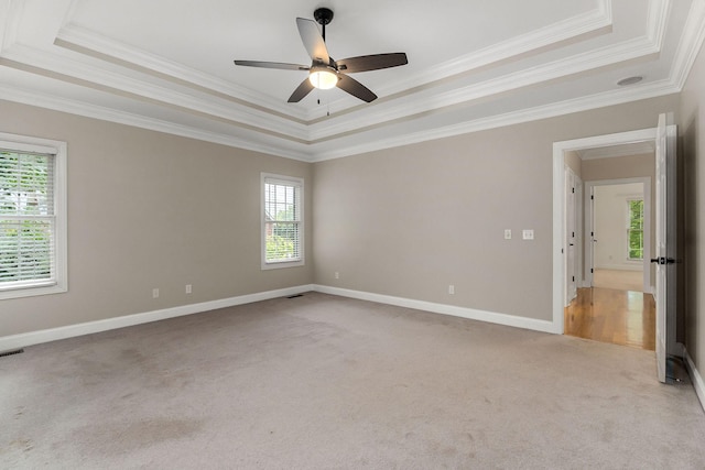 unfurnished room with a raised ceiling, light carpet, and baseboards