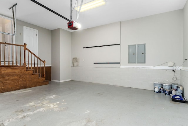 garage featuring concrete block wall, electric panel, and a garage door opener