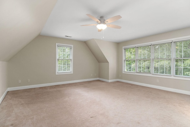 additional living space featuring lofted ceiling, visible vents, a ceiling fan, light carpet, and baseboards