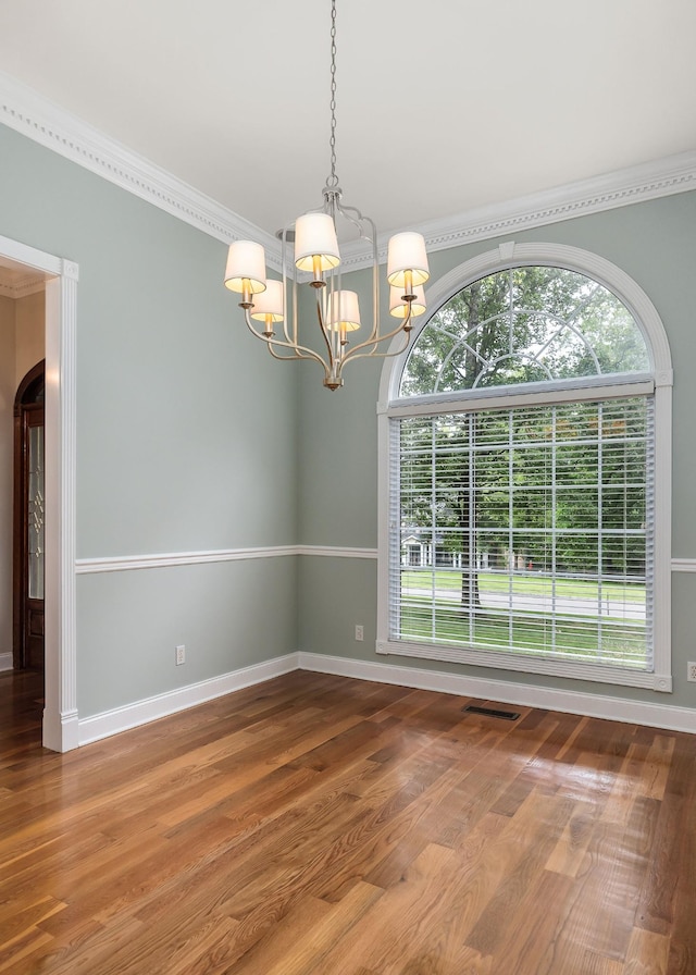 empty room featuring wood finished floors, visible vents, baseboards, and an inviting chandelier