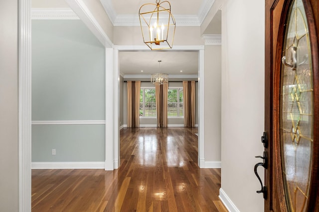 entrance foyer with crown molding, baseboards, dark wood-style floors, and a notable chandelier