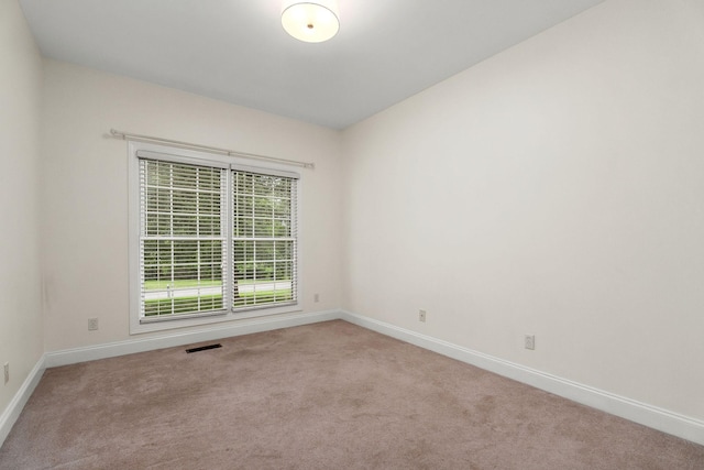 unfurnished room featuring light colored carpet, visible vents, and baseboards