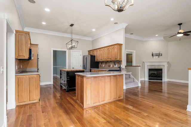 kitchen featuring a center island, light countertops, hanging light fixtures, open floor plan, and a sink