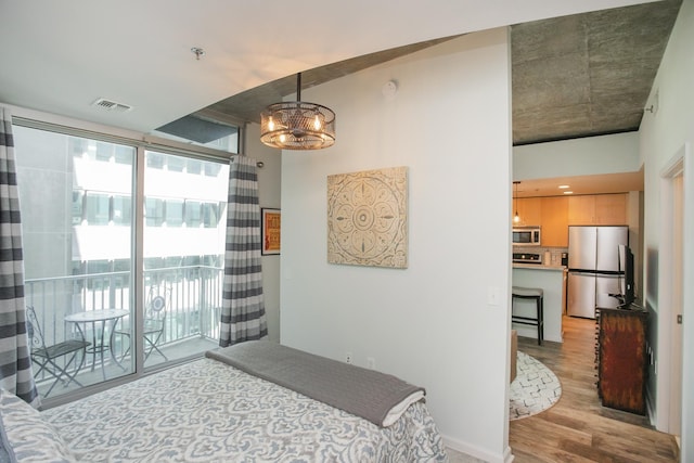 bedroom with a chandelier, stainless steel fridge, access to outside, and light hardwood / wood-style floors