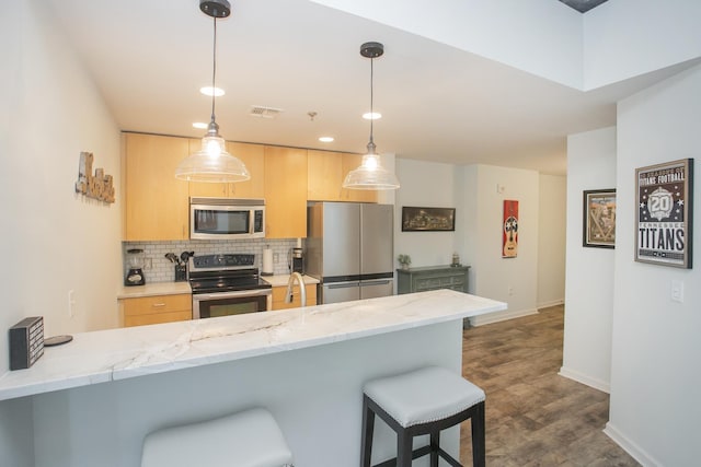 kitchen featuring light stone countertops, stainless steel appliances, backsplash, kitchen peninsula, and light brown cabinetry