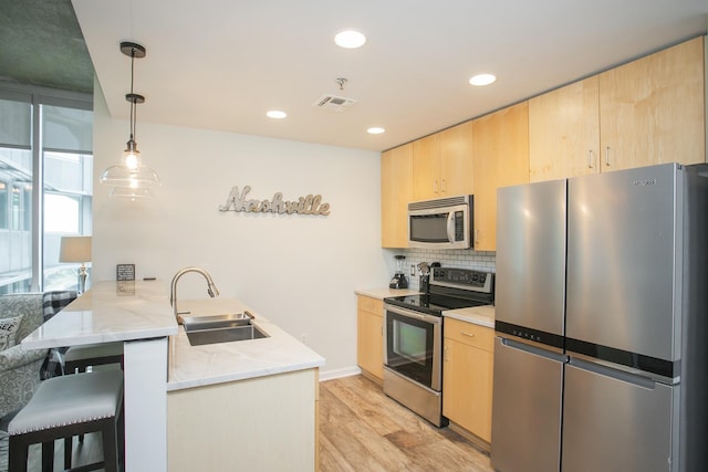 kitchen featuring sink, kitchen peninsula, light brown cabinetry, and appliances with stainless steel finishes