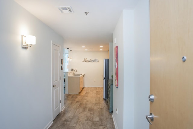 hall with sink and light hardwood / wood-style flooring