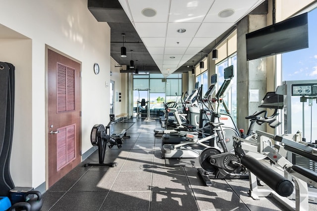 gym featuring a paneled ceiling and a wall of windows