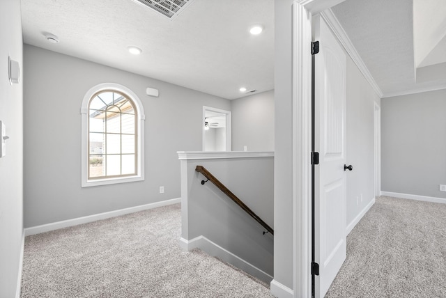 hallway with light carpet and a textured ceiling