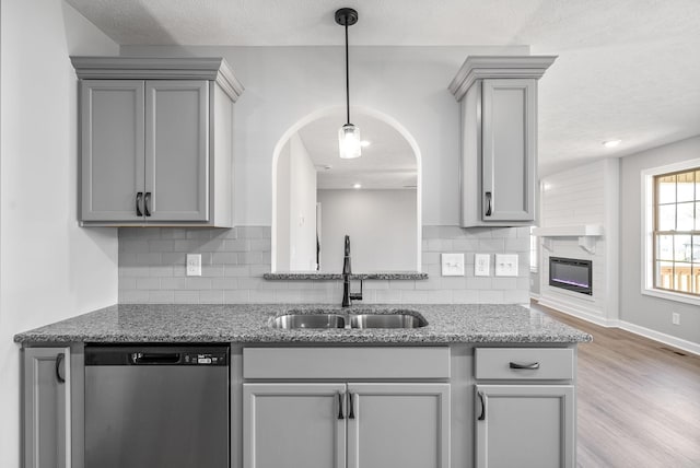 kitchen featuring dishwasher, sink, decorative backsplash, gray cabinets, and light wood-type flooring