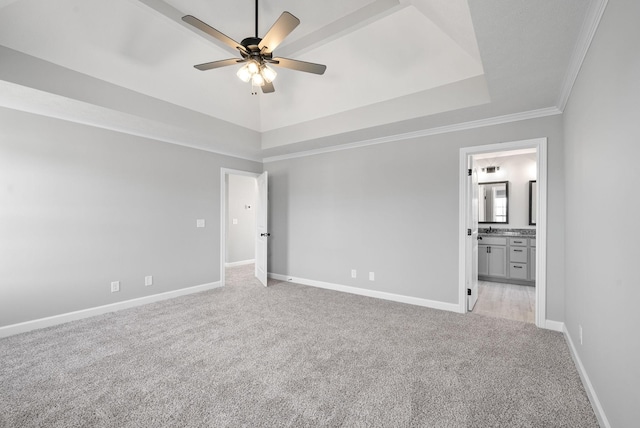 carpeted spare room featuring a raised ceiling, ceiling fan, and ornamental molding