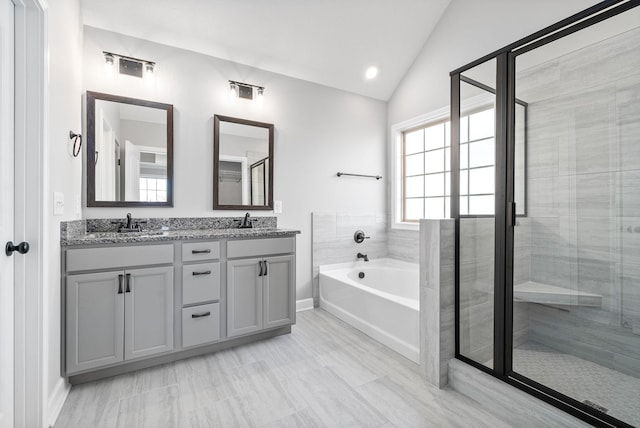 bathroom featuring vanity, independent shower and bath, and vaulted ceiling