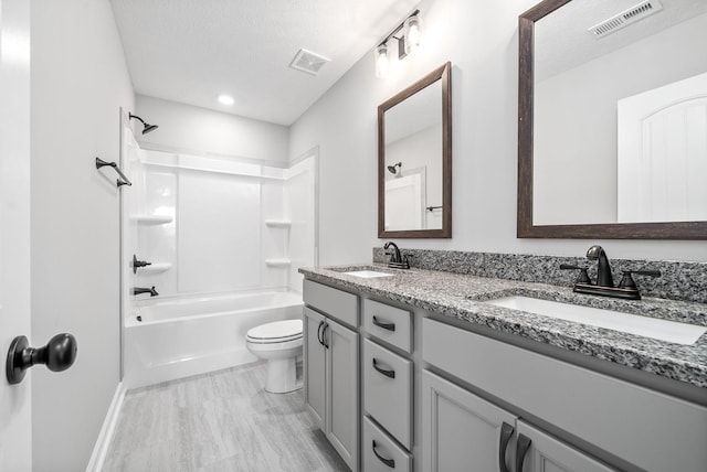 full bathroom featuring vanity, toilet, a textured ceiling, and shower / washtub combination