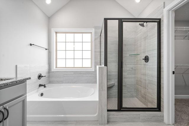 bathroom with plus walk in shower, vanity, and lofted ceiling