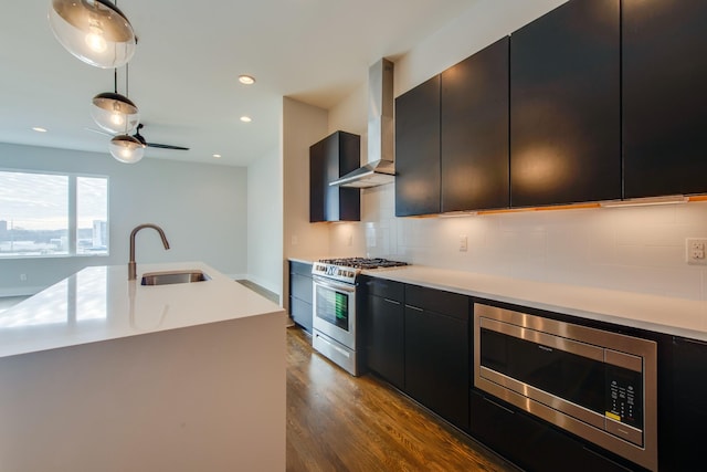 kitchen with backsplash, stainless steel appliances, a kitchen island with sink, sink, and decorative light fixtures