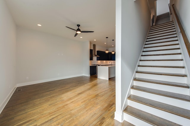 stairway featuring ceiling fan and wood-type flooring