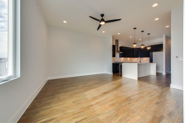 unfurnished living room featuring ceiling fan, dark hardwood / wood-style flooring, and sink