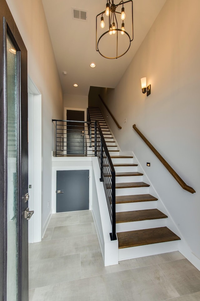 staircase with concrete floors and a notable chandelier