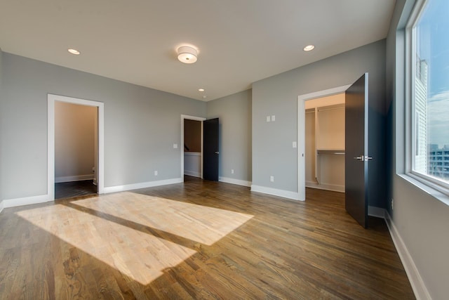 unfurnished bedroom with a walk in closet, dark wood-type flooring, and a closet