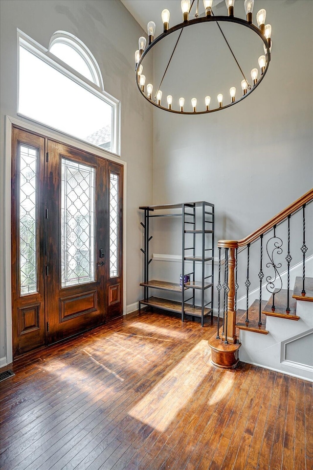 entrance foyer with a chandelier, wood-type flooring, and a towering ceiling