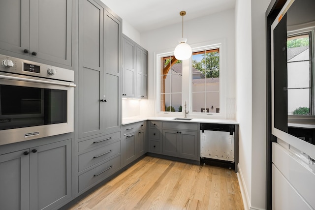 kitchen featuring gray cabinetry, a healthy amount of sunlight, light wood-type flooring, and appliances with stainless steel finishes