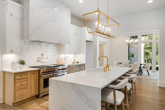 kitchen featuring white cabinets, double oven range, and an island with sink